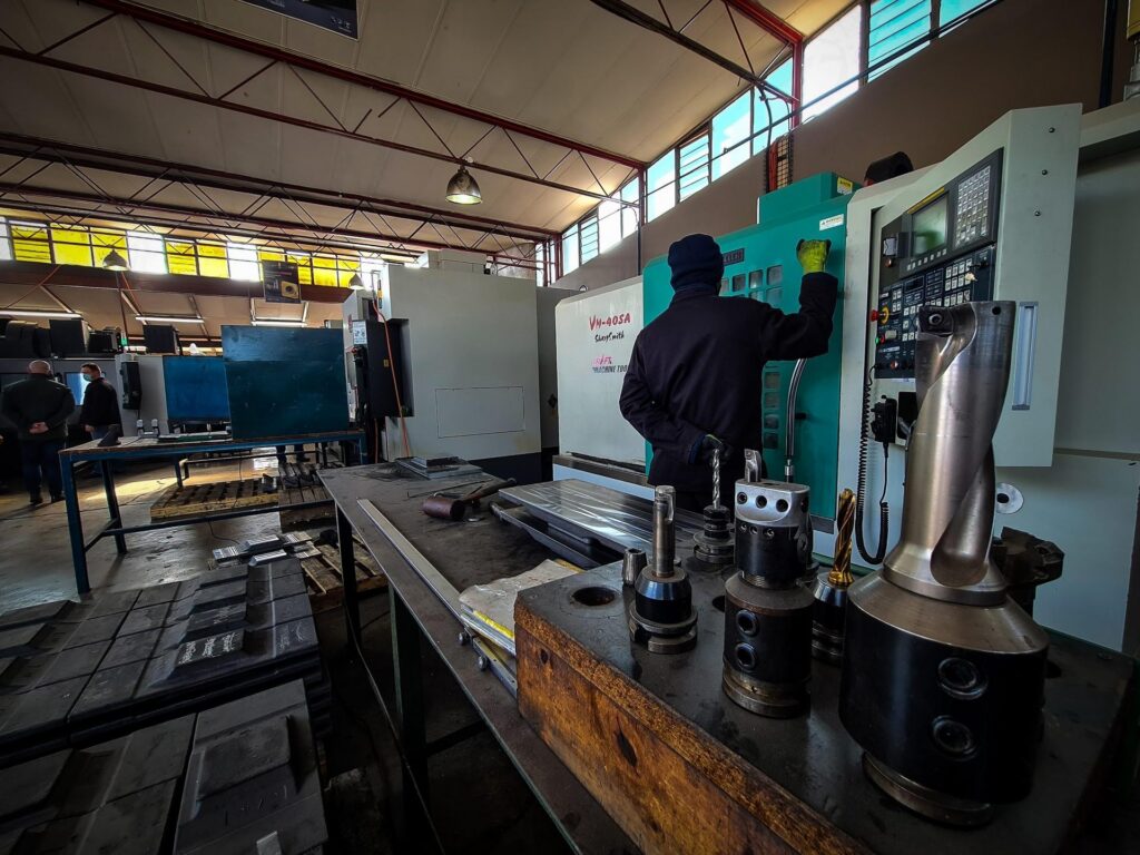 Operator at a CNC machine in the Bensch Forge machine shop, with tool holders on the workbench