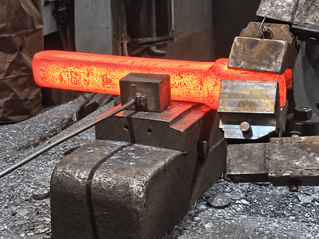 Close-up of a red-hot steel bar being shaped by open die forging at Bensch Forge